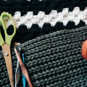 green scissors besides knitting sticks